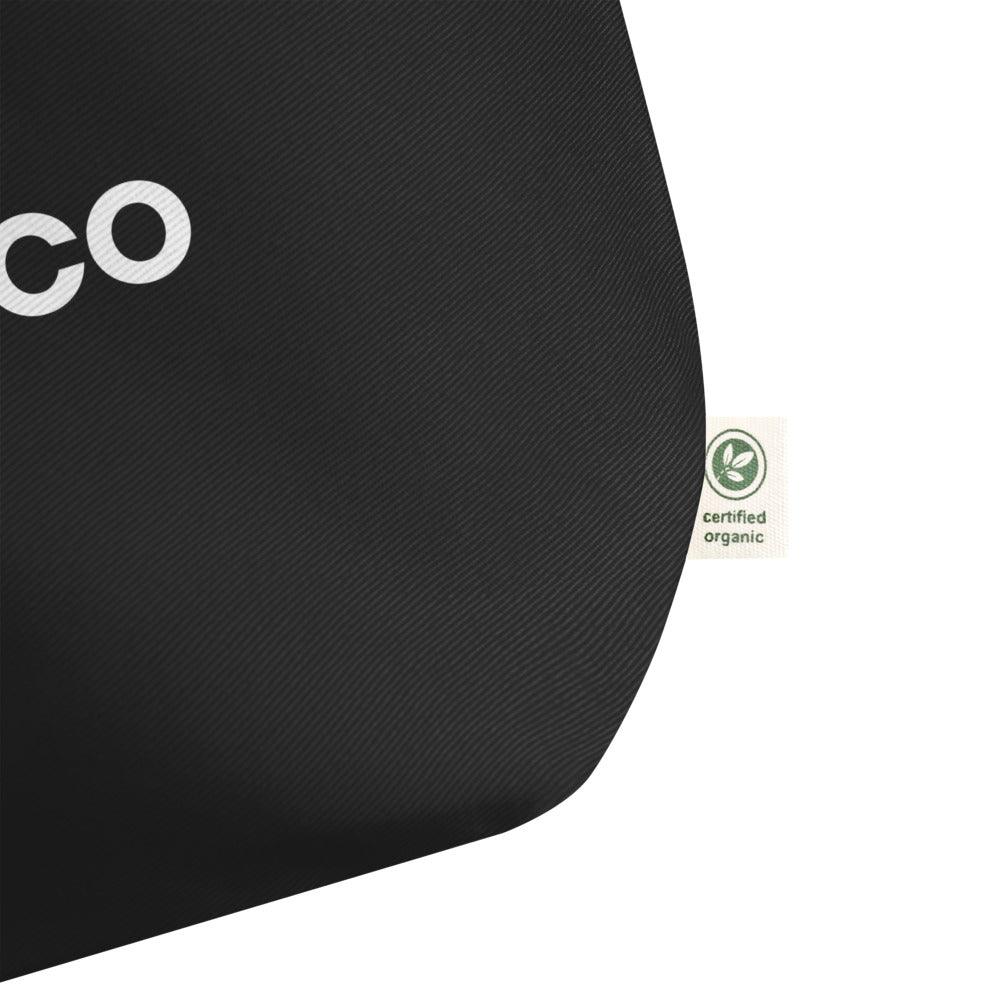 US Tico Large Organic Cotton Tote Bag in black textured cotton with partial white lettering and a certified organic tag
